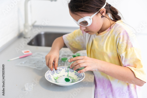 Enthusiastic little girl doing home science project, having a eureka moment. She has chemistry glassware with colorful liquids photo