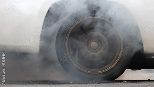 Drag car burning tire, Warm up tire before competition, Drag car wheel, Spinning wheel and smoke, Drag racing car burns rubber tires preparation for race. photo
