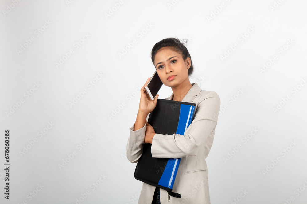 Cheerful corporate office lady holding a folder and a smartphone. Young woman in formal wear wearing white blazer against white background. Cheerful corporate office lady holding a folder and a smartphone. Young woman in formal wear wearing white blazer against white background.