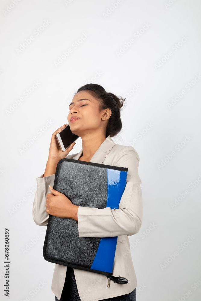 Cheerful corporate office lady holding a folder and a smartphone. Young woman in formal wear wearing white blazer against white background. Cheerful corporate office lady holding a folder and a smartphone. Young woman in formal wear wearing white blazer against white background.