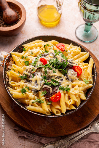 Penne pasta with mushroom sauce in a frying pan on the table, vegetarian comfort food vertical photo