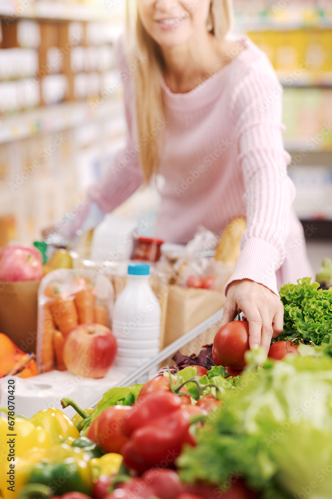 Happy woman buying fresh healthy vegetables at the supermarket