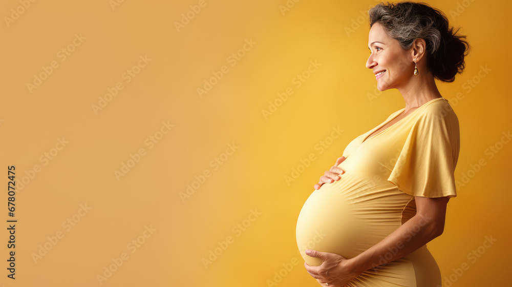 Pregnant mature woman on pastel yellow background with copy space. Late pregnancy, gynecological services for management of pregnancy, In Vitro Fertilization. - obrazy, fototapety, plakaty 