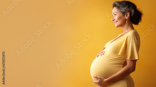 Pregnant mature woman on pastel yellow background with copy space. Late pregnancy, gynecological services for management of pregnancy, In Vitro Fertilization. photo