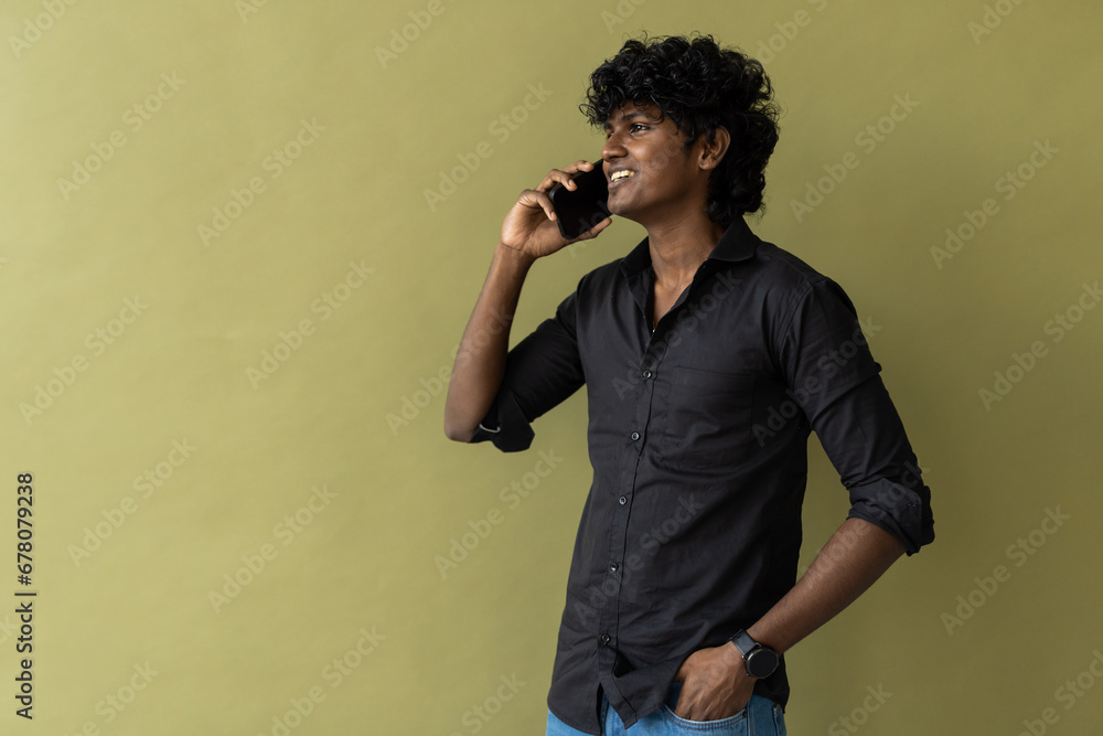 Young handsome Indian man talking on mobile phone on green background Young handsome Indian man talking on mobile phone on green background