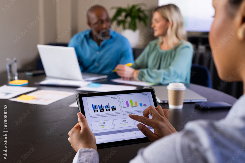 Businesswoman using tablet at meeting with diverse colleagues discussing and using laptop Businesswoman using tablet at meeting with diverse colleagues discussing and using laptop