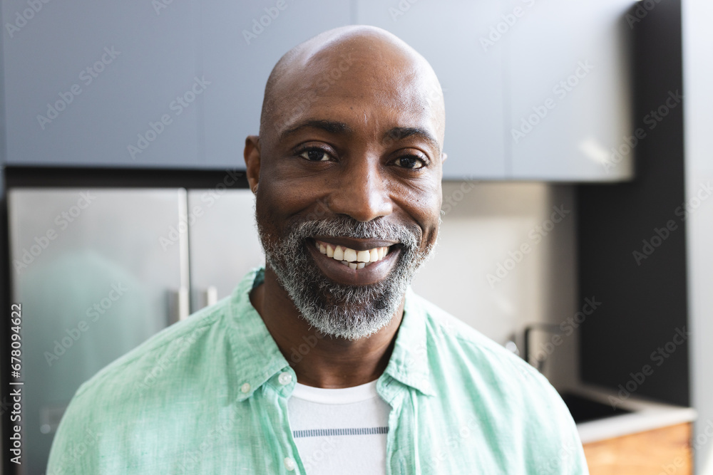 Portrait of happy bald african american mature man with beard smiling in sunny kitchen at home Portrait of happy bald african american mature man with beard smiling in sunny kitchen at home