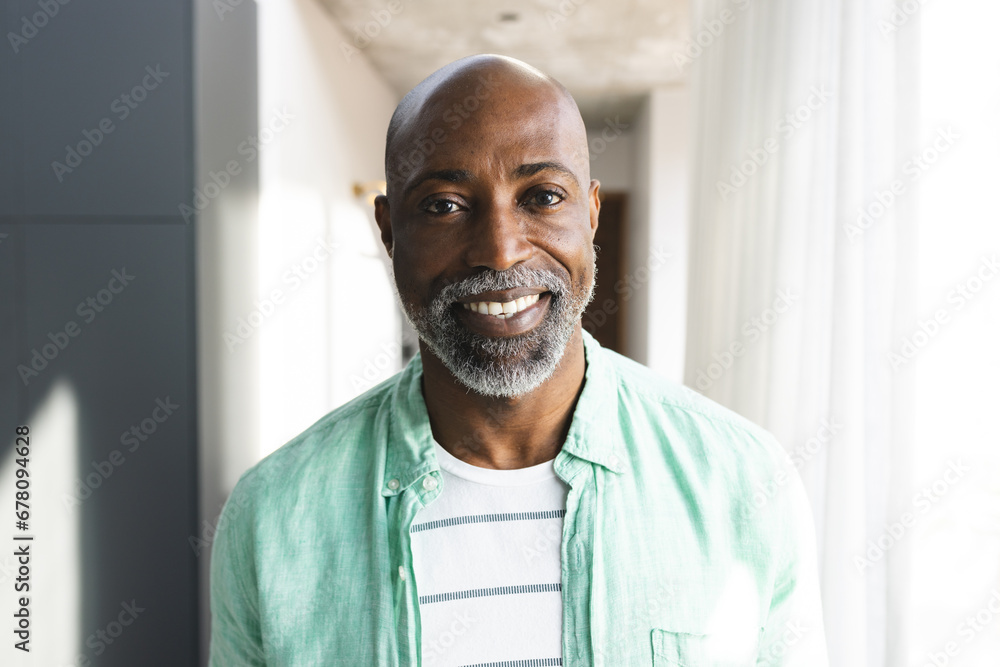 Portrait of happy bald african american mature man with beard smiling in sunny room at home Portrait of happy bald african american mature man with beard smiling in sunny room at home