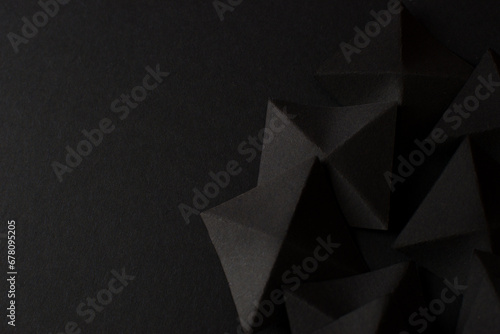 Black abstract geometric shapes on dark background, top view, copy space
