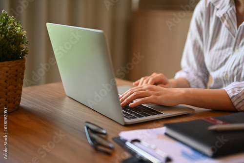 Cropped shot of businesswoman hands typing on laptop keyboard searching information on internet