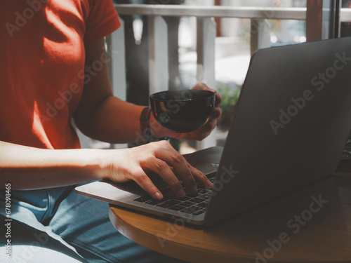Young woman working on laptop while drinking hot coffee