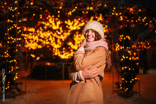 Young beautiful woman near the Christmas tree on the eve of Christmas. A girl walks through the city decorated for the New Year. New Year's lights in the evening winter city. © Konstantin Zibert