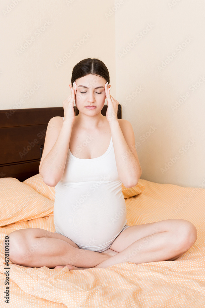 Young pretty pregnant woman suffering from headache at home in bed Young pretty pregnant woman suffering from headache at home in bed