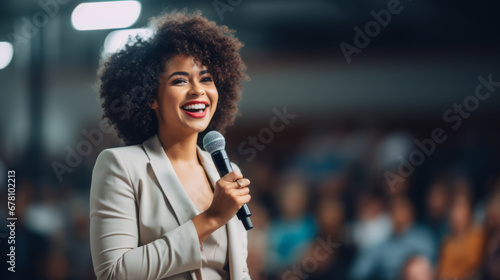 Black afro American businesswoman delivering a powerful keynote address at a conference standing on stage with confidence addressing a diverse audience with her insights in the business world photo