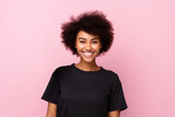 cheerful young African American woman with a radiant smile, wearing a black t-shirt, set against a soft pink background