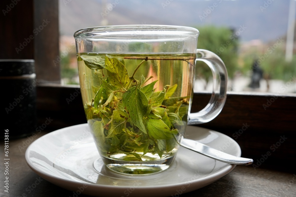 Cup of Green Coca Tea in a clear glass cup on a saucer with a spoon. Cup of Green Coca Tea in a clear glass cup on a saucer with a spoon.