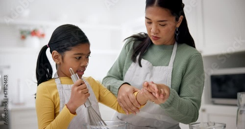 Mother, child and baking together in kitchen for love, care and learning recipe for dessert, food or cooking. Mom roll up clothes sleeve of girl for teaching, whisk ingredients and helping at home photo