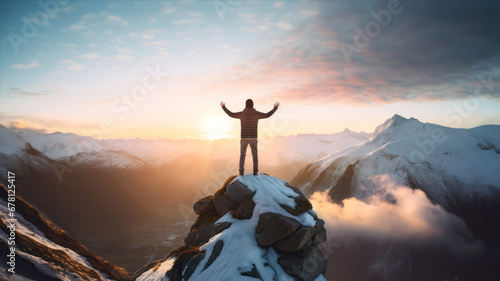 Man standing on top of a mountain with his arms raised against beautiful landscape © Ula