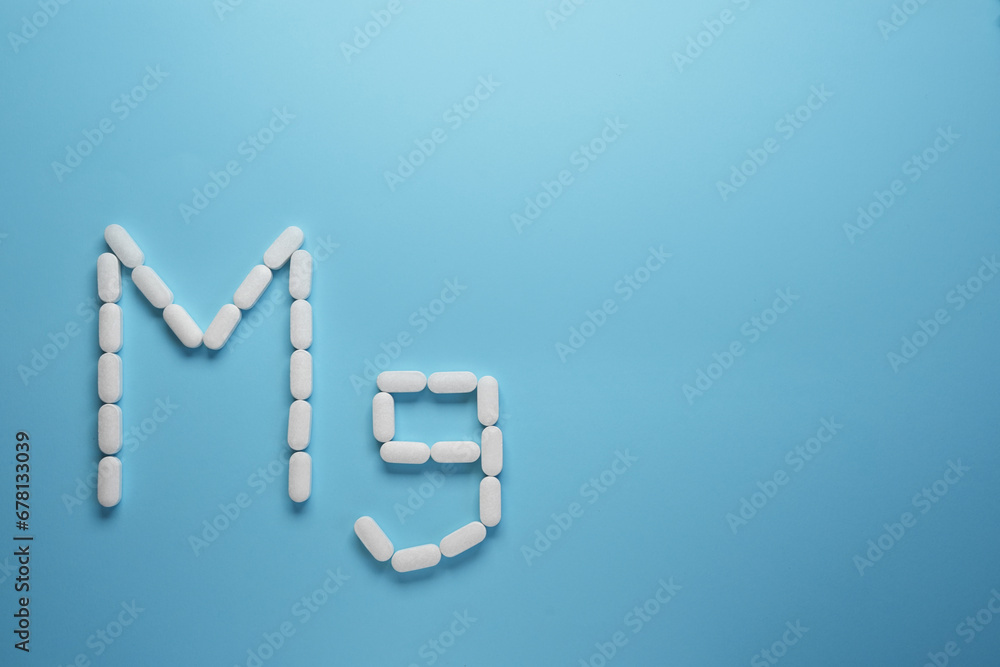 Mg element made of pills on blue background. Top view, flat lay. Space for text. Mg element made of pills on blue background. Top view, flat lay. Space for text.