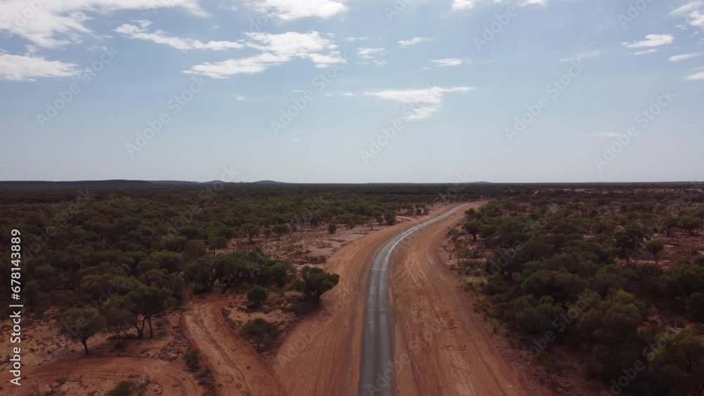 Drone ascending over a very remote country road surrounded with red soil and trees in the Australian outback Drone ascending over a very remote country road surrounded with red soil and trees in the Australian outback