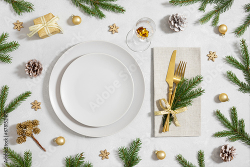 Christmas table setting with empty plate, gold cutlery and festive accessories on white background. New Year party. Top view, flat lay.