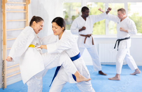 Karate with two female athletes practicing, training and sparring in fight class. Healthy, fit and active women in uniform learning self defense for safety and health