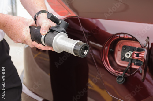 A man holds the high pressure (350 bar) nozzel at a hydrogen fuel filling pump station. photo