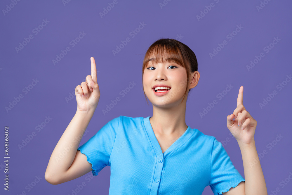 Cute asian woman raise hands up, showing promo, pointing fingers up, stand purple background Cute asian woman raise hands up, showing promo, pointing fingers up, stand purple background