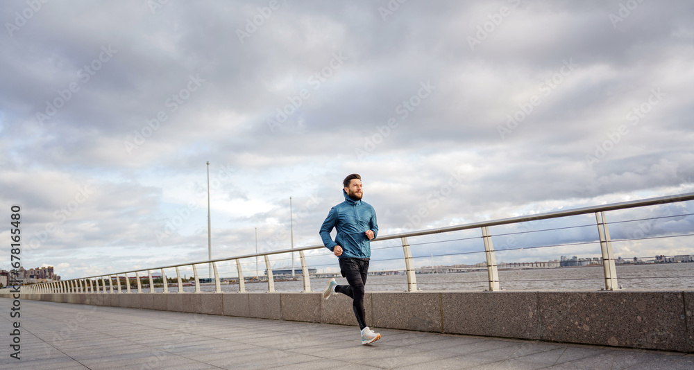 A running man in fitness clothes training alone. A positive athlete is preparing for a triathlon with daily long-distance training. A running man in fitness clothes training alone. A positive athlete is preparing for a triathlon with daily long-distance training.