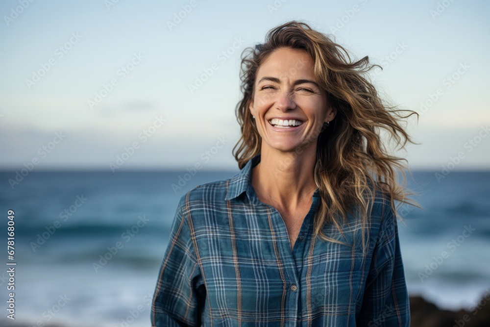 Portrait of a smiling woman in her 40s wearing a comfy flannel shirt against a stunning ocean reef. AI Generation