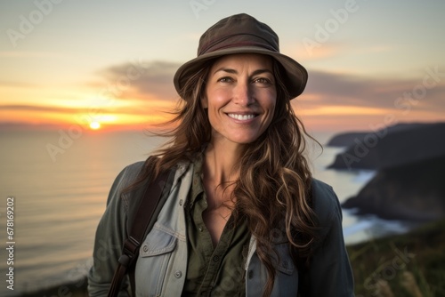 Portrait of a satisfied woman in her 40s wearing a rugged jean vest against a beautiful beach sunset. AI Generation