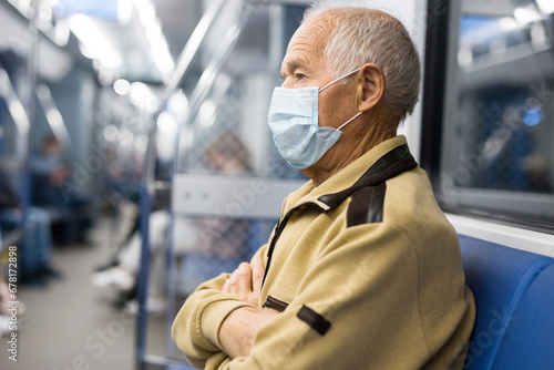 Portrait of adult man in disposable mask traveling in subway train during daily