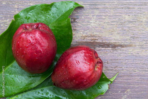 Pomerac fruits (Syzygium malaccense) has other names are Malay Apple, Chompoo Mameaw, Rose apple. It's pear-like fruit with calyx attached to end of fruit, dark red color, placed on its green leaves. photo