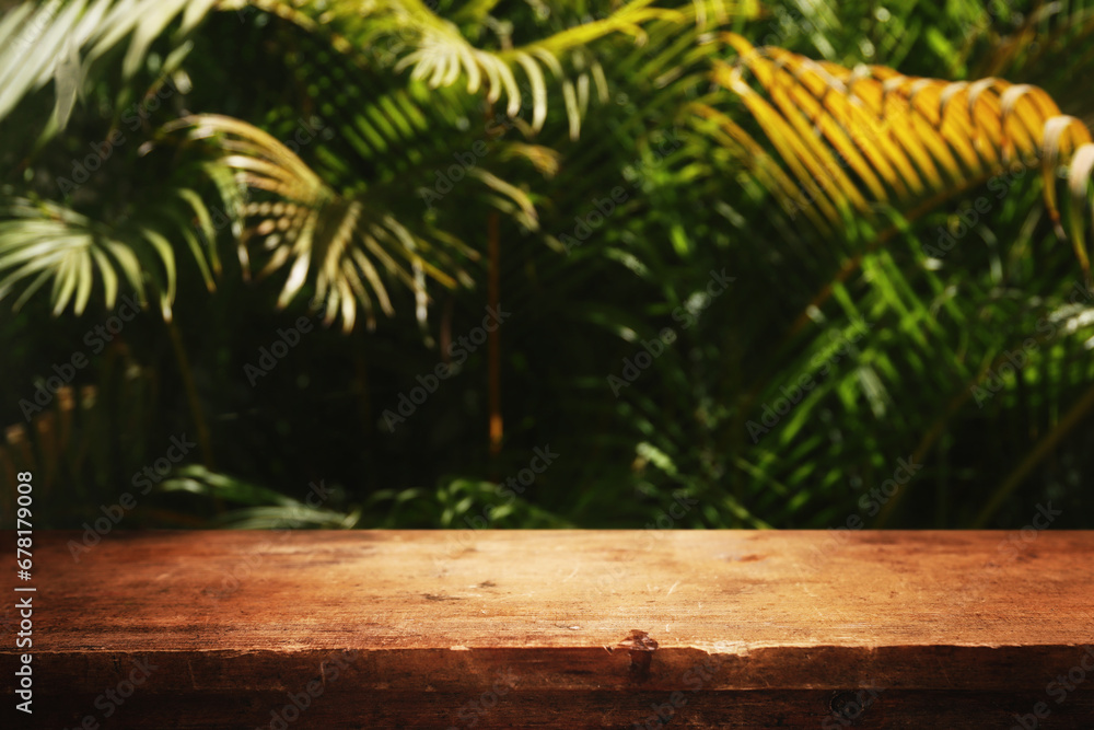 wooden table in front of tropical green floral background. for product display and presentation.