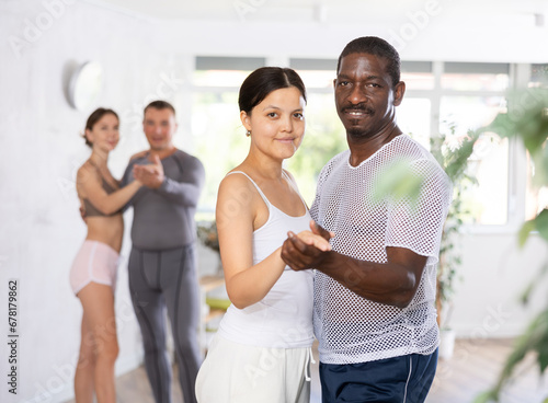 Smiling woman enjoying dance with African american male partner in modern dancing class