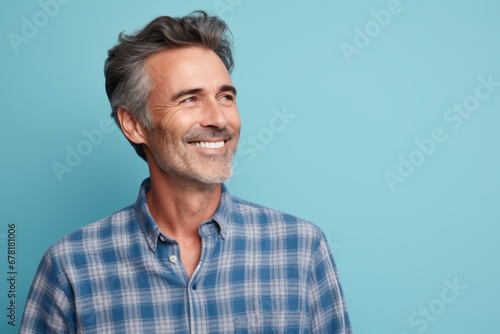 Portrait of a glad man in his 50s wearing a comfy flannel shirt against a pastel blue background. AI Generation photo