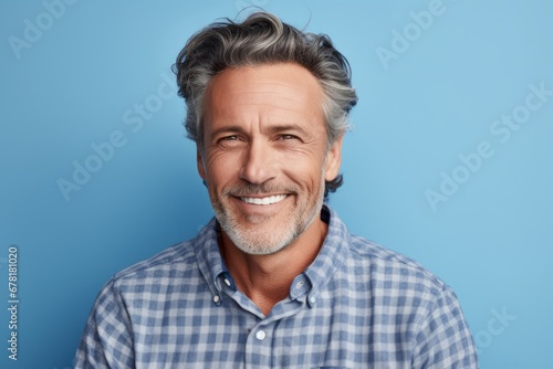 Portrait of a glad man in his 50s wearing a comfy flannel shirt against a pastel blue background. AI Generation