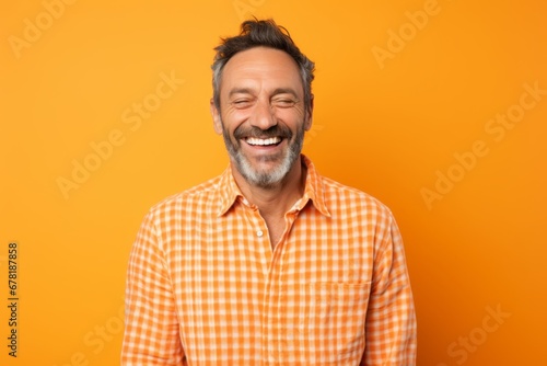 Portrait of a joyful man in his 40s wearing a comfy flannel shirt against a pastel orange background. AI Generation