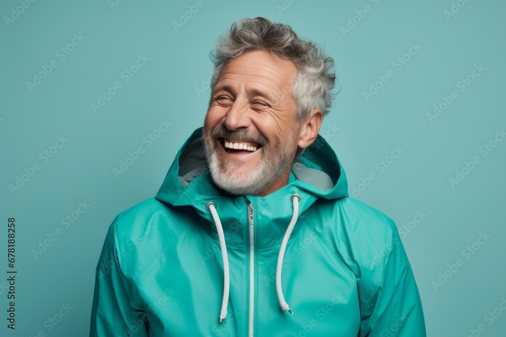 Portrait of a cheerful man in his 50s wearing a lightweight packable anorak against a pastel teal background. AI Generation Portrait of a cheerful man in his 50s wearing a lightweight packable anorak against a pastel teal background. AI Generation