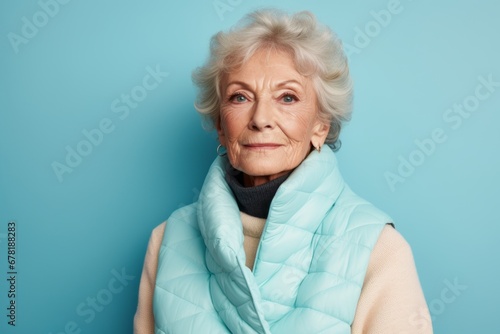 Portrait of a content woman in her 70s dressed in a thermal insulation vest against a pastel teal background. AI Generation photo