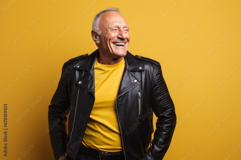 Fototapeta premium Portrait of a smiling man in his 60s sporting a classic leather jacket against a soft yellow background. AI Generation