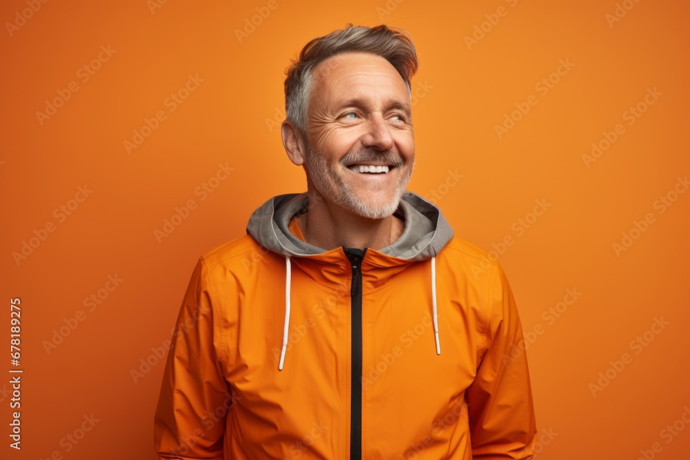 Portrait of a happy man in his 50s wearing a functional windbreaker against a soft orange background. AI Generation Portrait of a happy man in his 50s wearing a functional windbreaker against a soft orange background. AI Generation