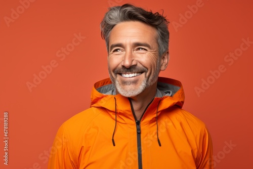 Portrait of a happy man in his 50s wearing a functional windbreaker against a soft orange background. AI Generation © CogniLens