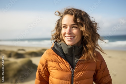 Portrait of a satisfied woman in her 20s sporting a quilted insulated jacket against a sandy beach background. AI Generation
