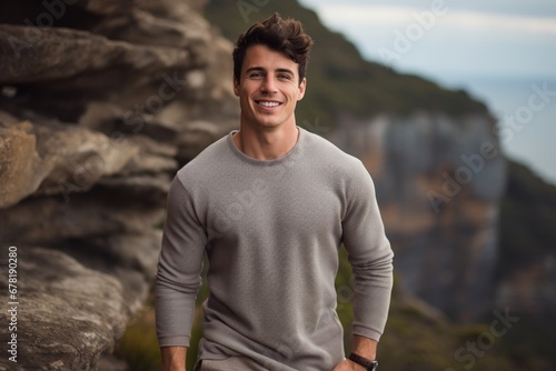 Portrait of a glad man in his 20s showing off a thermal merino wool top against a rocky cliff background. AI Generation