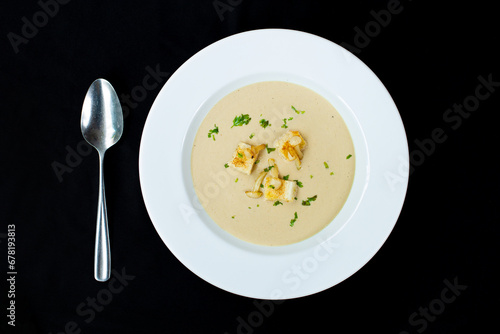 Delicious Mushroom Soup with Presly on top Served on a White Plate with Spoon. Isolated Top view over black background for Restaurant  Blog social media print and other commercial Use. photo