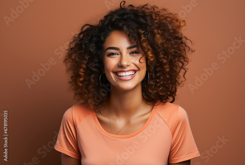 young pretty woman with curly hair laughs heartily into the camera in front of an orange background © Marcus Jacobi