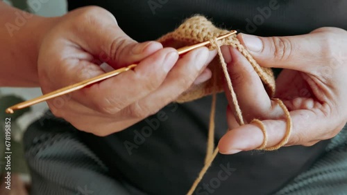 Close-up of hand woman holding crochet hook , enjoy knitting , sit on garden chair. hand of female knits handmade scarf at home, lady handwork craft hobby concept, 4k. photo