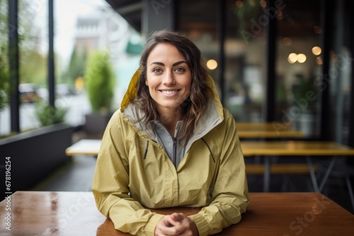Portrait of a smiling woman in her 30s wearing a lightweight packable anorak against a serene coffee shop background. AI Generation photo