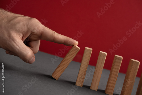 Domino has Fallen in a Row. Domino theory. Effect. Hand with Finger is Pointing and Pushing the Falling Wood Blocks. Risk Management, Revolution Concept. Affect Business. Closeup. Manifestation. Red